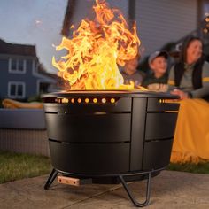 a fire pit sitting on top of a cement slab next to a woman and child