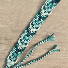 two blue and white beaded bracelets with tassels on a wooden surface