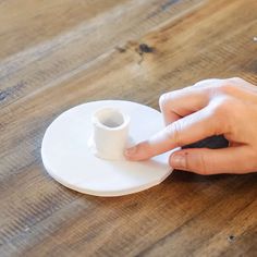 a person's hand is pressing the button on a coffee cup holder that sits on top of a wooden table