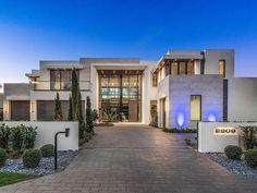 the entrance to a modern home at dusk with blue lights on it's windows