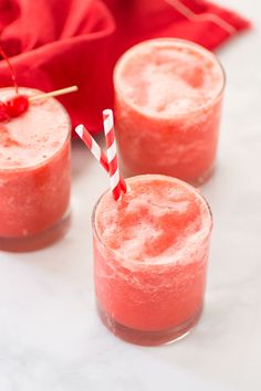 three glasses filled with strawberry milkshakes on top of a white table next to a red napkin