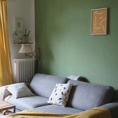 a living room with green walls and a blue couch in front of a radiator