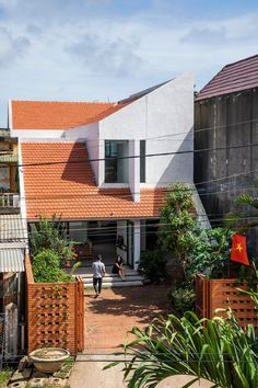 two people are walking towards a house with red roof tiles on the outside and inside