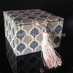 a large blue and white box with a tassel on it's end sitting on a black surface