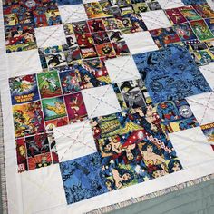 a quilt made with comic book covers on a bed sheet that is laying on top of a table