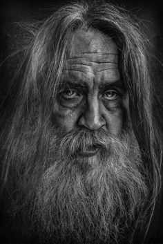 black and white photograph of an old man with long hair, beard and big eyes