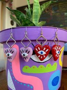 three heart shaped earrings hanging from a potted plant