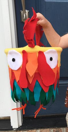 a person is holding up a colorful bird decoration on the front door sill to show off it's feathers