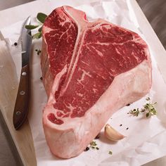 a piece of raw meat sitting on top of a cutting board next to a knife