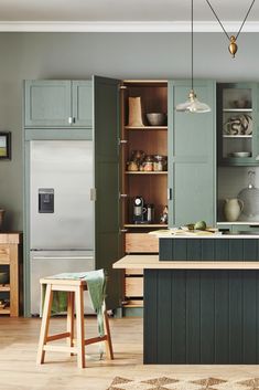 a kitchen with green cabinets and wooden floors