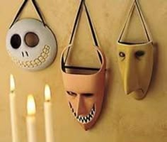 three masks are hanging on the wall next to candles