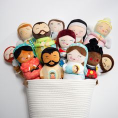 a basket filled with lots of different stuffed dolls sitting on top of a white surface