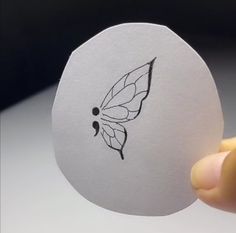 a hand holding an egg with a butterfly drawn on it