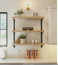 a kitchen with white brick walls and stainless steel dishwasher in the middle, open shelving