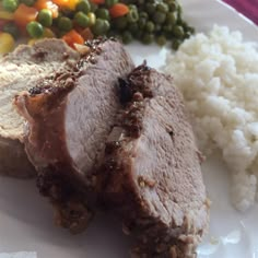 a plate with meat, rice and peas on it