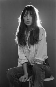 a black and white photo of a woman sitting on a stool