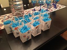 small bags filled with blue candy sitting on top of a table next to wine glasses