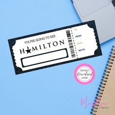 a ticket sitting on top of a desk next to a laptop and notepad with the words, you're going to see hamilton