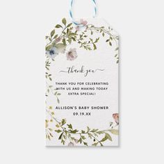 a thank card with flowers and leaves on it, the tag is hanging from a blue ribbon