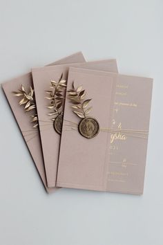 three wedding cards with gold leaves and a wax stamp on the front one has a coin