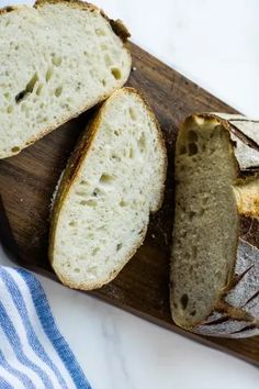 two loaves of bread sit on a cutting board next to a blue and white towel