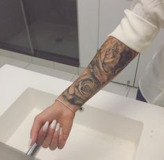 a person with a rose tattoo on their arm is holding onto a piece of metal