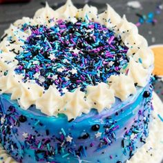 a blue cake with sprinkles and white frosting on a platter