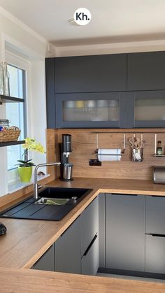 a kitchen with gray cabinets and wooden counter tops, along with a stainless steel sink