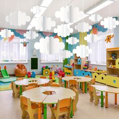 a room filled with lots of wooden tables and chairs next to windows covered in clouds