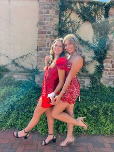 two beautiful young women standing next to each other in front of a brick wall and ivy covered building