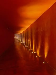 a long hallway with red walls and lights on the wall at each end in front of it