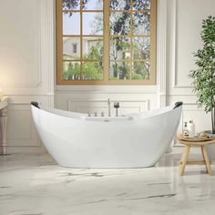 a white bathtub sitting in front of a window next to a potted plant