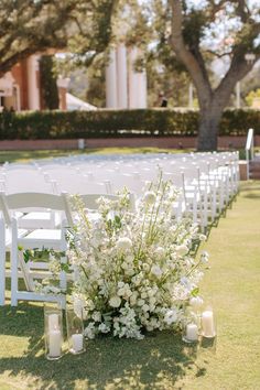 the aisle is lined with white flowers and candles for an outdoor ceremony in front of a building