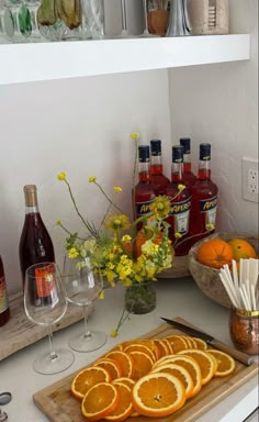 orange slices on a cutting board next to bottles of wine and flowers in a vase