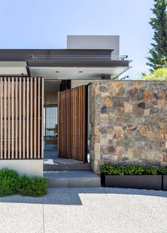 the entrance to a modern home with stone walls and wood slats on the doors