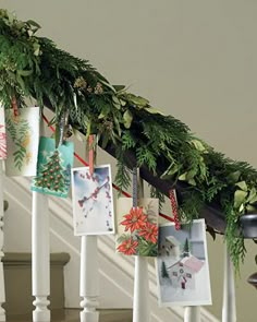 christmas cards are hanging on the banisters in front of the stairs with evergreen garland and pine cones