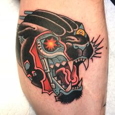 a tattoo on the leg of a man with a black and red tiger head design