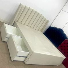 a white couch sitting on top of a floor next to a red and blue chair