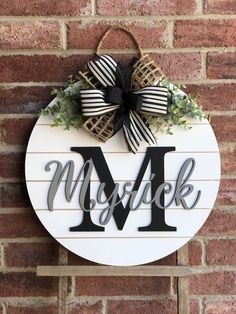 a wooden sign with the letter m and a bow hanging on it's side