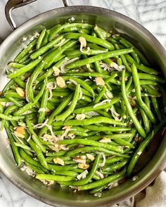 green beans and almonds in a pan on a marble counter top, ready to be cooked