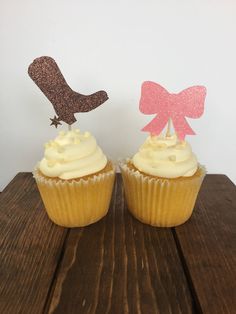 two cupcakes sitting on top of a wooden table next to each other and one has a football helmet