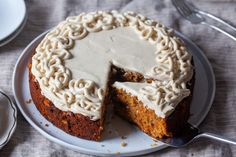 a cake with white frosting is on a plate next to a fork and knife