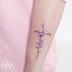 a woman with a cross tattoo on her arm and purple flowers in the middle of her arm