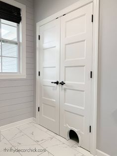 an empty room with two white doors and a black blind on the window sill