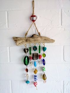 a wall hanging made out of driftwood and glass bead beads with a boat on it