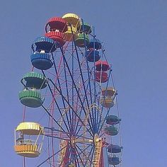 the ferris wheel is brightly colored and has many seats on it's sides,