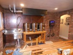 a kitchen area with wooden benches and metal pots on the stove top, in front of a brick wall