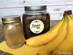 some bananas are sitting on a table next to a jar of tea and a banana