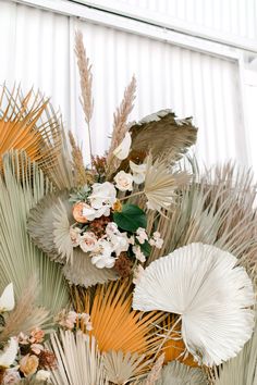 an arrangement of palm leaves and flowers on display