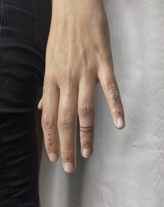 a woman's hand with two small tattoos on her left thumb and one finger